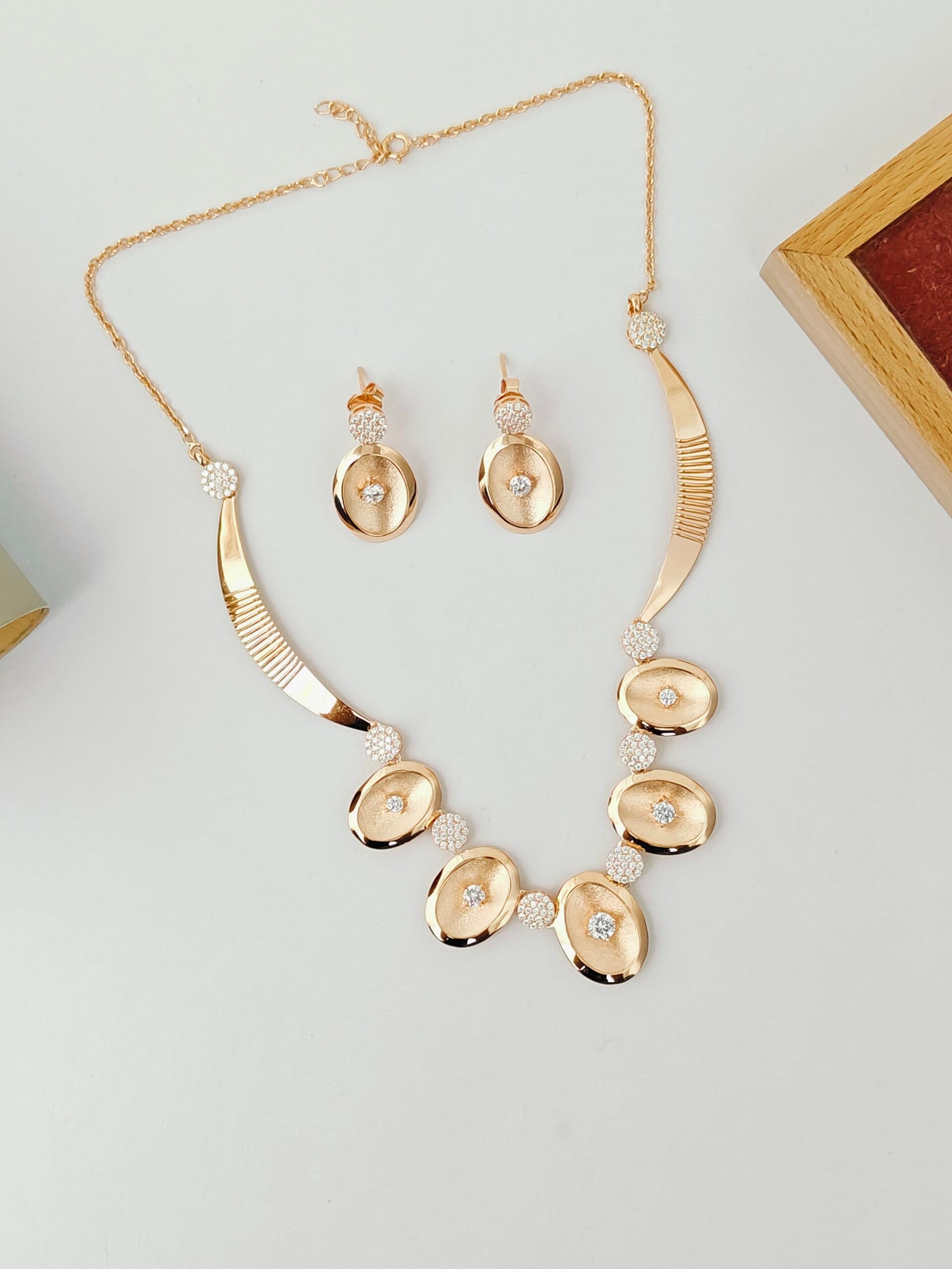 Gold necklace and earrings set on a light gray background